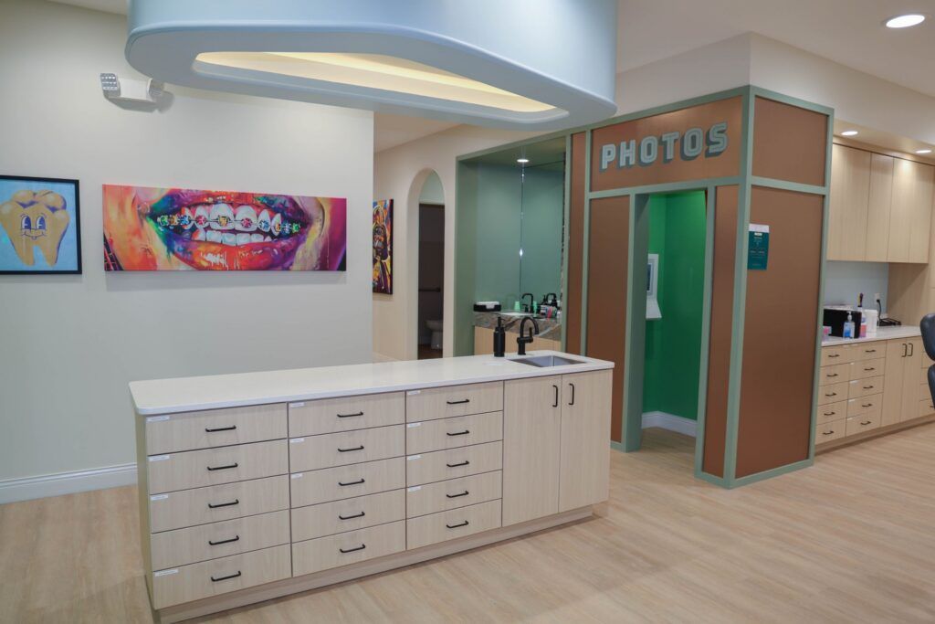 Elite Orthodontics Studio office clinical area with cabinetry, braces artwork and a photo booth