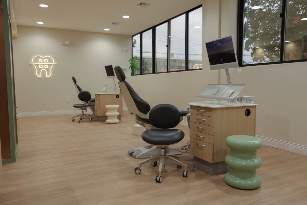 Elite Orthodontics Studio office treatment area with dental chairs and a glowing tooth sign