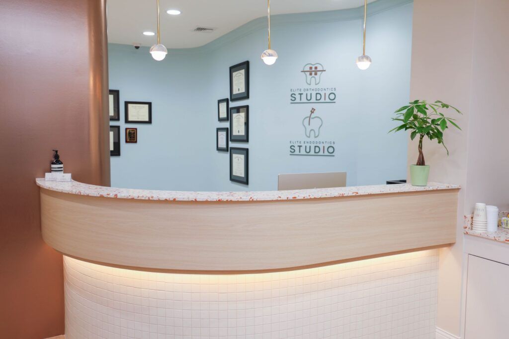 Elite Orthodontics Studio office reception desk with the practice logos on the wall